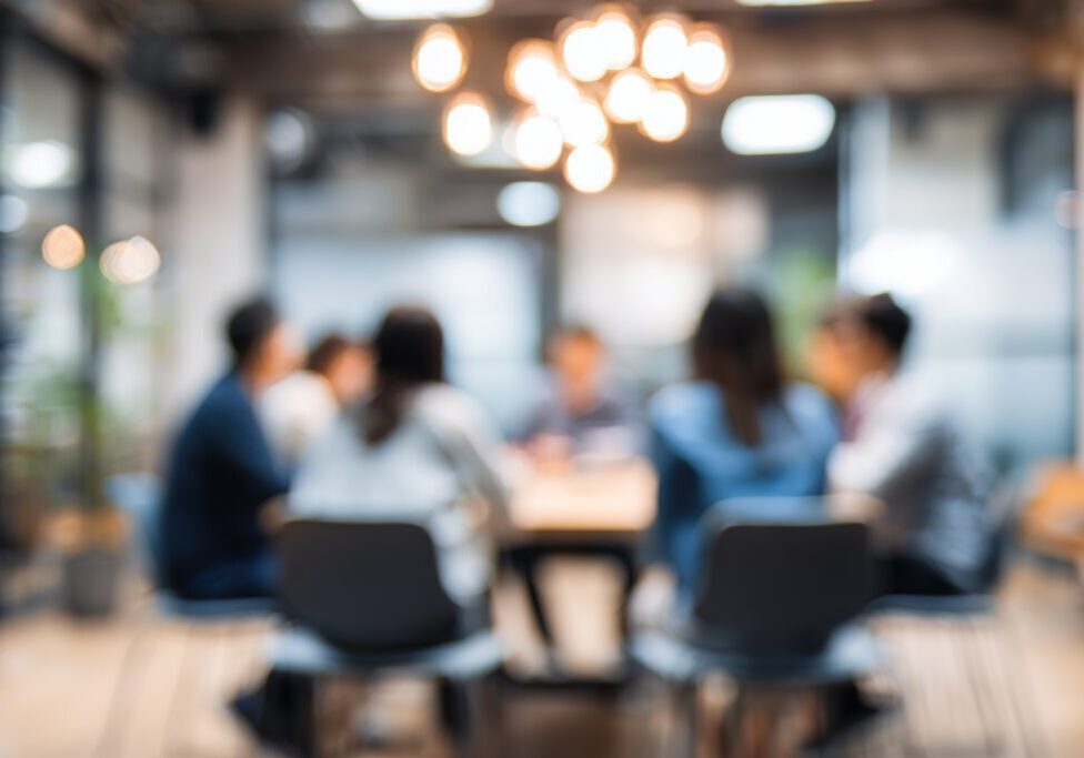 Blur a group of employees are sitting in a meeting and listening to what their boss is saying about business in the organization in the small meeting room at the office in the morning. High quality